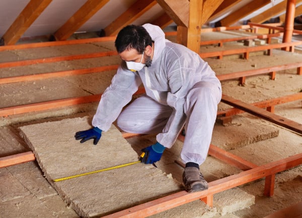 ENERGY man laying insulation in attic shutterstock 245439406 e1456418197516